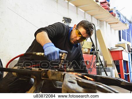 Picture - Mechanic cutting engine part with grinder. Fotosearch