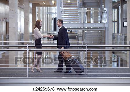 Mid adult businesswoman greeting businessman on conference centre walkway View Large Photo Image Stock Photo - Mid adult businesswoman greeting businessman on conference centre walkway. Fotosearch
