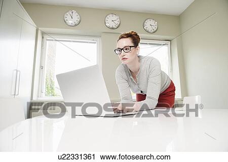 Mid adult businesswoman leaning forward to use laptop View Large Photo Image Stock Image - Mid adult businesswoman leaning forward to use laptop. Fotosearch