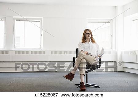 Stock Photo - Mid adult businesswoman on office chair in new office. Fotosearch