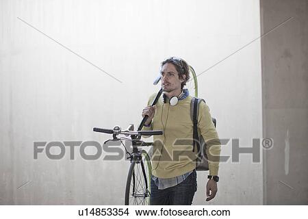 Mid adult man carrying bicycle through city underpass View Large Photo Image Picture - Mid adult man carrying bicycle through city underpass. Fotosearch