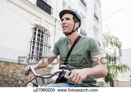 Stock Photography - Mid adult man cycling in city street. Fotosearch