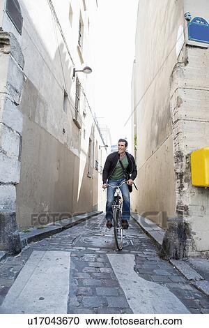 Mid adult man cycling on narrow cobble street, Paris, France View Large Photo Image Stock Image - Mid adult man cycling on narrow cobble street, Paris, France. Fotosearch