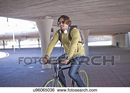 Mid adult man cycling through city underpass View Large Photo Image Stock Photograph - Mid adult man cycling through city underpass. Fotosearch