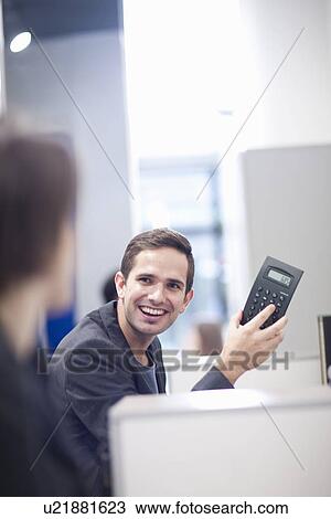 Stock Image - Mid adult man holding calculator. Fotosearch
