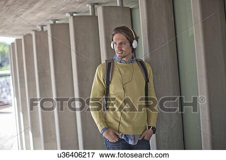 Stock Photo - Mid adult man listening to headphones in city underpass. Fotosearch