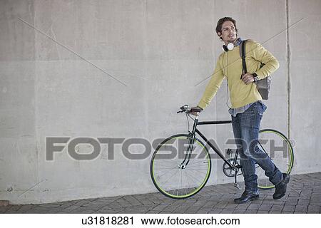 Mid adult man pushing bicycle through city underpass View Large Photo Image Stock Image - Mid adult man pushing bicycle through city underpass. Fotosearch