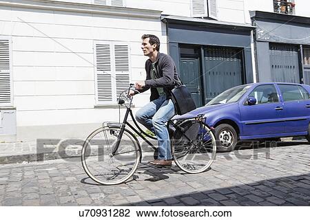 Mid adult man speeding down cobbled city street on bicycle View Large Photo Image Stock Image - Mid adult man speeding down cobbled city street on bicycle. Fotosearch