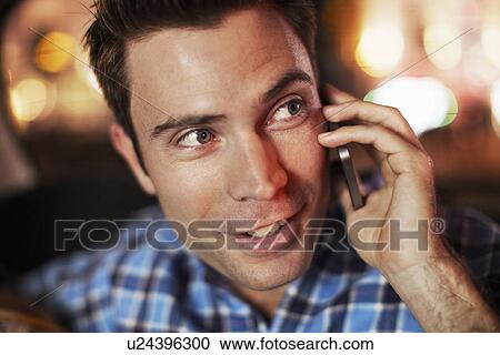 Stock Image - Mid adult man talking on smartphone in city taxi at night. Fotosearch