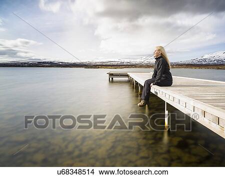 Picture - Mid adult woman gazing from pier, Thingvellir, Iceland. Fotosearch
