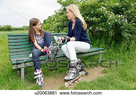 Mother and daughter putting on rollerblades in park View Large Photo Image Stock Image - Mother and daughter putting on rollerblades in park. Fotosearch