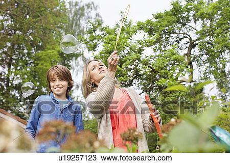 Mother and son playing with soap bubbles in garden View Large Photo Image Stock Image - Mother and son playing with soap bubbles in garden. Fotosearch