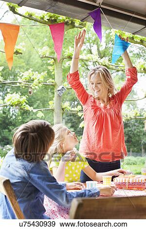 Mother chatting with children and putting up bunting View Large Photo Image Stock Photo - Mother chatting with children and putting up bunting. Fotosearch