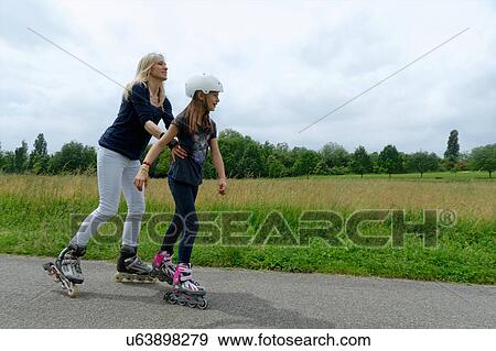 Mother holding onto daughter whilst rollerblading in park View Large Photo Image Stock Photo - Mother holding onto daughter whilst rollerblading in park. Fotosearch