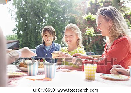 Stock Photo - Mother serving birthday cake to family at birthday party. Fotosearch