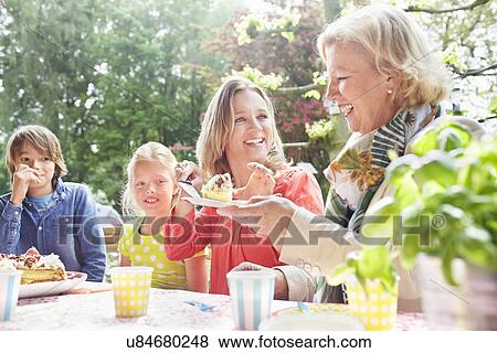 Mother serving birthday cake to family at birthday party View Large Photo Image Stock Photo - Mother serving birthday cake to family at birthday party. Fotosearch