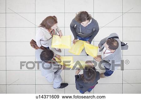 Overhead view of businesswomen and men with paperwork in conference centre atrium View Large Photo Image Stock Photo - Overhead view of businesswomen and men with paperwork in conference centre atrium. Fotosearch