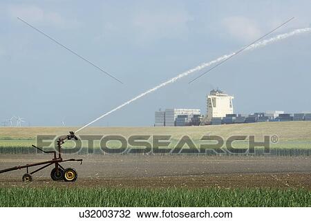 Plant crop irrigation due to prolonged drought. A container ship leaving Antwerp harbour in the background, Rilland, Zeeland, Netherlands View Large Photo Image Stock Image - Plant crop irrigation due to prolonged drought. A container ship leaving Antwerp harbour in the background, Rilland, Zeeland, Netherlands. Fotosearch