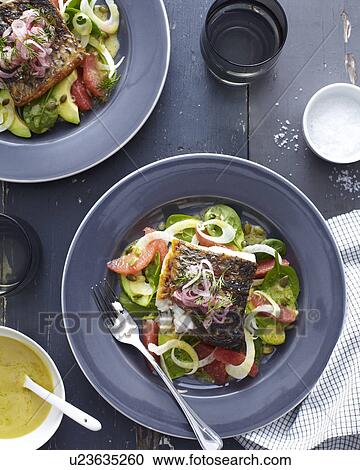 Stock Image - Plate of barramundi fish with vegetables and a herb garnish. Fotosearch