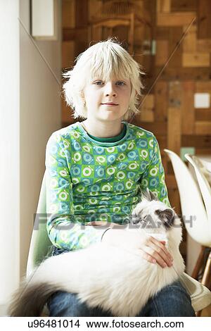 Picture - Portrait of boy with cat on his lap in kitchen. Fotosearch
