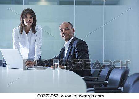 Stock Image - Portrait of businesswoman and man at boardroom table. Fotosearch