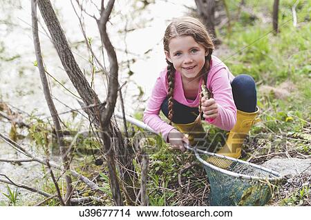 Picture - Portrait of girl holding up frog and fishing net. Fotosearch