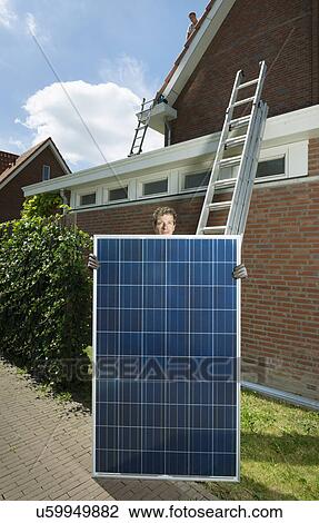 Stock Image - Portrait of male with solar panel for roof of new home, Netherlands. Fotosearch
