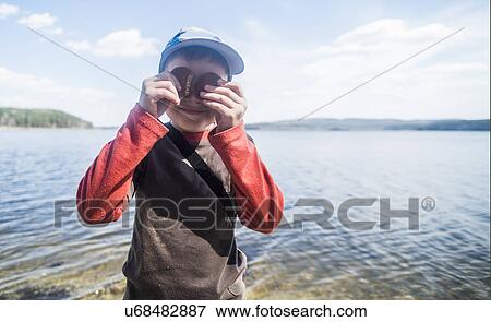Portrait of mischievous boy with biscuits over eyes at lakeside View Large Photo Image Stock Photo - Portrait of mischievous boy with biscuits over eyes at lakeside. Fotosearch