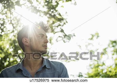 Stock Photography - Portrait of serious young man in park. Fotosearch