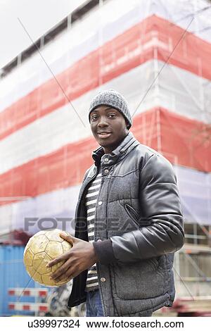 Portrait of smiling young man on street holding soccer ball View Large Photo Image Picture - Portrait of smiling young man on street holding soccer ball. Fotosearch