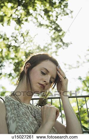 Portrait of sullen young woman with hand on her head in park View Large Photo Image Stock Image - Portrait of sullen young woman with hand on her head in park. Fotosearch