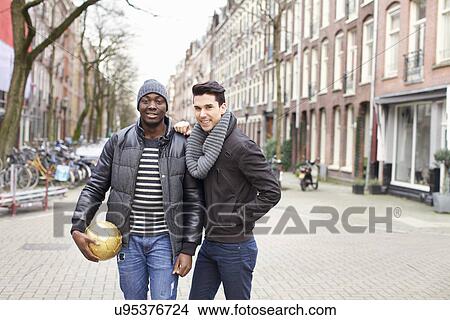 Portrait of two young men on street holding soccer ball, Amsterdam, Netherlands View Large Photo Image Picture - Portrait of two young men on street holding soccer ball, Amsterdam, Netherlands. Fotosearch