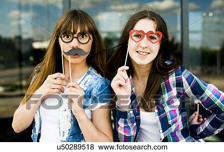 Portrait of two young women holding up mustache and eyeglass costume masks View Large Photo Image Stock Photo - Portrait of two young women holding up mustache and eyeglass costume masks. Fotosearch