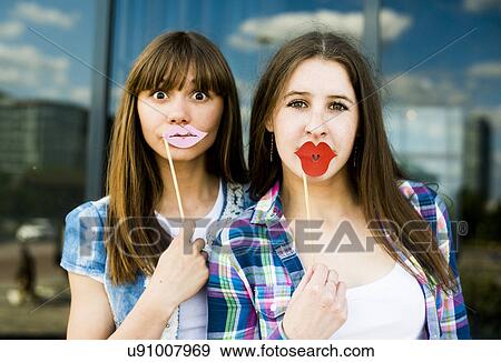 Portrait of two young women holding up lip costume masks View Large Photo Image Stock Photo - Portrait of two young women holding up lip costume masks. Fotosearch