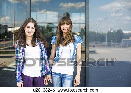 Stock Photography - Portrait of two young women in front of glass fronted office exterior. Fotosearch