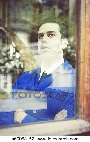 Stock Image - Portrait of young man in vintage jacket gazing through window. Fotosearch
