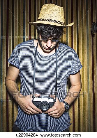 Portrait of young man looking down at vintage camera View Large Photo Image Picture - Portrait of young man looking down at vintage camera. Fotosearch