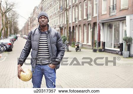 Portrait of young man on street holding soccer ball, Amsterdam, Netherlands View Large Photo Image Stock Photo - Portrait of young man on street holding soccer ball, Amsterdam, Netherlands. Fotosearch