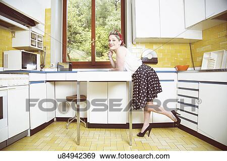 Stock Photo - Portrait of young woman in vintage clothes in vintage kitchen. Fotosearch
