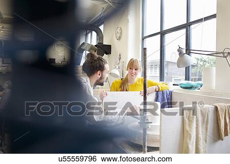 Stock Photograph - Potter couple working in ceramic workshop. Fotosearch