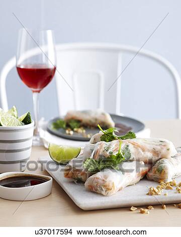 Picture - Prawn spring rolls on chopping board with tamarind. Fotosearch