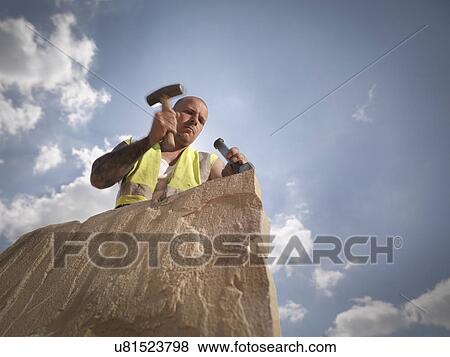 Stock Photo - Quarry worker splitting sandstone in Yorkshire stone quarry. Fotosearch