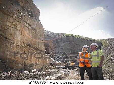 Picture - Quarry workers inspecting rock strata in stone quarry. Fotosearch
