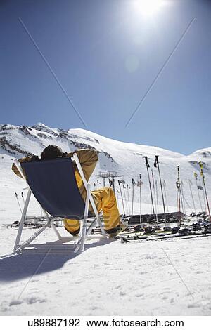 Rear view of mid adult male skier sitting on deck chair, Austria View Large Photo Image Stock Image - Rear view of mid adult male skier sitting on deck chair, Austria. Fotosearch