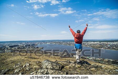 Stock Photo - Rear view of young female hiker celebrating on top of mountain. Fotosearch