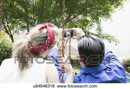 Rear view of young vintage couple taking selfie with camera in garden View Large Photo Image Stock Photo - Rear view of young vintage couple taking selfie with camera in garden. Fotosearch