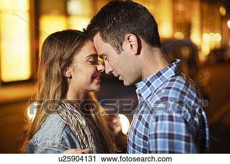 Stock Image - Romantic couple face to face city street at night. Fotosearch