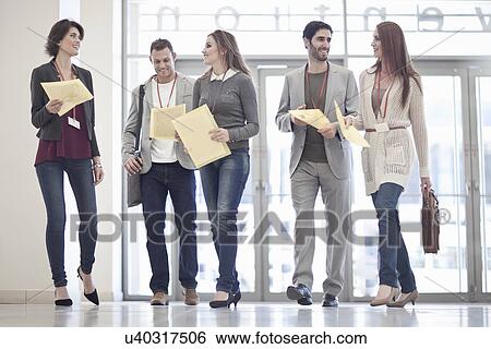 Row of businessmen and women with paperwork in conference centre atrium View Large Photo Image Stock Photograph - Row of businessmen and women with paperwork in conference centre atrium. Fotosearch