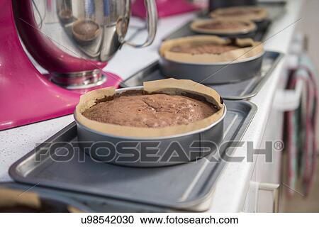 Stock Image - Row of cakes cooling off on top of ovens in bakery. Fotosearch