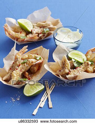 Stock Image - Salt and pepper seafood with lime slices and dipping sauce. Fotosearch
